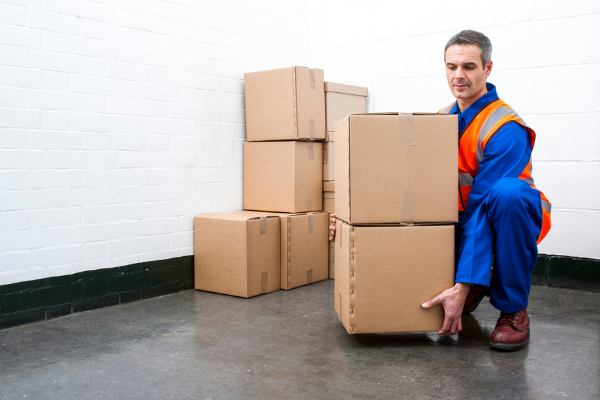 A person demonstrating correct manual handling while lifting boxes in a warehouse