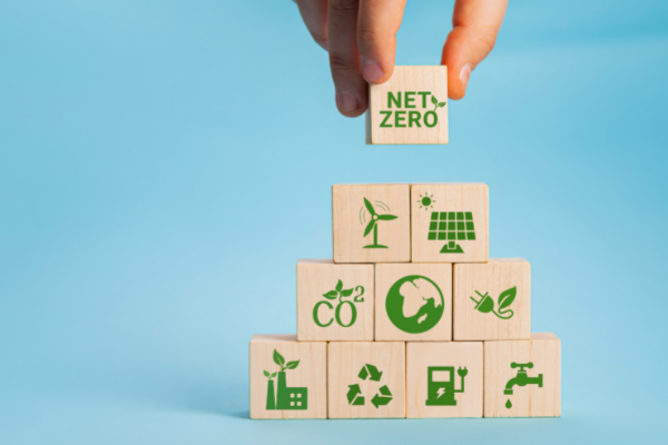 A set of building blocks against a pale blue background, each block printed with a different environment icon - including an earth, the recycling logo, a wind turbine and net zero