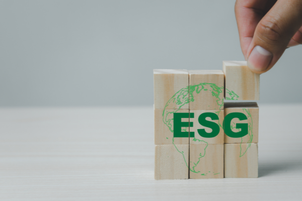 A hand putting together small wooden building blocks that spell out "ESG" and an image of a globe